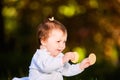 Close-up of cute baby girl sitting in the park and eats the snack at warm day. Royalty Free Stock Photo