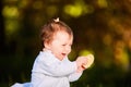 Close-up of cute baby girl sitting in the park and eats the snack at warm day. Royalty Free Stock Photo