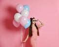 Close-up of cute blond girl standing in a studio, smiling widely and playing with blue and pink baloons. Royalty Free Stock Photo