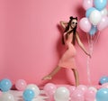 Close-up of cute blond girl standing in a studio, smiling widely and playing with blue and pink baloons. Royalty Free Stock Photo