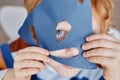 Close-up of cute blueeyed little boy covering face with blue paper mask