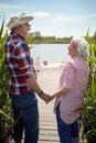 Close up of cute caucasian senior couple holding hands, looking each other, smiling,  standing by the river Royalty Free Stock Photo