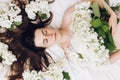 Close up of cute charming nice pretty woman lying on cozy bed with fresh spring flowers. Head shot portrait dreamy young brunette Royalty Free Stock Photo