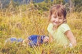 Close up cute child girl lie on a meadow in the grass against mountain background. Happy child have a rest in mountains. Happiness