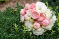 Wedding bouquet of pink peonies and white eustoma flowers against a background of a bush of green leaves. Royalty Free Stock Photo