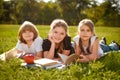 Close up of cute happy little school kids with notebooks laying in outdoor grassy park. group portrait looking at camera