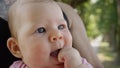 CLOSE UP: Cute little baby girl puts her tiny hand in her mouth while resting in strong dad`s lap. Royalty Free Stock Photo