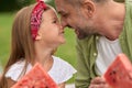 Close up of cute little girl and her loving dad touching noses while eating watermelon, family having a picnic in the Royalty Free Stock Photo