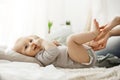 Close up of cute newborn baby lying on bed, looking aside while mother playing and touching his little legs. Baby Royalty Free Stock Photo