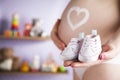 Happy pregnant woman, baby shoes in her hands Royalty Free Stock Photo