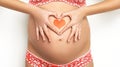 Close up of a cute pregnant belly with red heart. Royalty Free Stock Photo