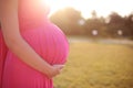 Close up of cute pregnant belly in sunset outside in the park, o