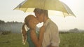 CLOSE UP: Cute young couple smiles and kisses in the refreshing summer rain. Royalty Free Stock Photo