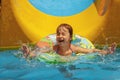 Close up cute young girl into pool after going down water slide during summer. Summer holiday, adventure and happy childhood Royalty Free Stock Photo