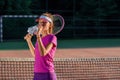 Close up cute young girl in sporty cap drinking water from plastic bottle after hard tennis training on the outdoor Royalty Free Stock Photo