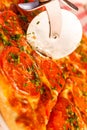 Close up Cuts with a pizza cutter. Pizza Margarita. Delicious hot food sliced and served on white platter. Menu photo Royalty Free Stock Photo