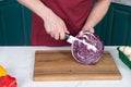 Close up of cutting half of red cabbage. Closeup of man hands with knife and red cabbage. Red cabbage on wooden cutting board Royalty Free Stock Photo