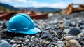 Close up of a cyan Working Helmet on Gravel. Blurred Construction Site Background