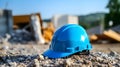 Close up of a cyan Working Helmet on Gravel. Blurred Construction Site Background