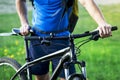 Close-up of cyclist with bicycle on background of green grass in summer.
