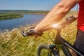 Close-up of the cyclist holding bicycle on the meadow in the countryside against beautiful landscape.