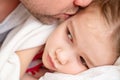 Dad kisses little sick daughter sleeping on bed. Royalty Free Stock Photo