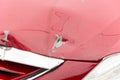 Close up of damaged car hood in the crash accident with hole on the red vehicle and peeled paint Royalty Free Stock Photo