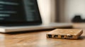 Damaged external hard drive lying on wooden surface near laptop screen displaying corrupted code, revealing potential