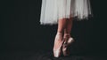 Close-up of dancing legs of ballerina wearing white pointe on a black background Royalty Free Stock Photo