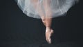 Close-up of dancing legs of ballerina wearing white pointe on a black background Royalty Free Stock Photo