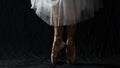 Close-up of dancing legs of ballerina wearing white pointe on a black background Royalty Free Stock Photo