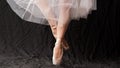 Close-up of dancing legs of ballerina wearing white pointe on a black background Royalty Free Stock Photo