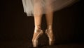 Close-up of dancing legs of ballerina wearing white pointe on a black background Royalty Free Stock Photo