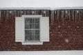 CLOSE UP: Dangerous snow covered roof with long icicles hanging off the gutters. Royalty Free Stock Photo