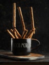Close-up. On a dark background, a black cup with cinnamon sticks. Oriental spices and seasonings, aromatic additives for hot