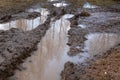 close-up of dark brown path with muddy pits and large puddles. Dirt road in village. Royalty Free Stock Photo