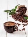 Close-up of dark coffee cup with espresso, roasted coffee beans in the bag of burlap, on white wooden background. Near coffee Royalty Free Stock Photo