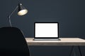 Close up of dark designer office desk with white mock up laptop on wooden desk. Royalty Free Stock Photo