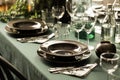 Close-up of a dark dining set on an elegant table with green cloth in a restaurant interior. Real photo