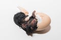 Close-up of dark newborn cute little small chick trying to get out of hatching chicken egg shell on white background