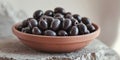 Close Up of Dark Olives in a Terracotta Bowl on Stone Surface. Royalty Free Stock Photo