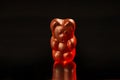 Close-up of a dark red gummy bear on a black background