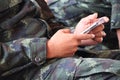 Close-up of a dark-skinned Asian male soldier holding a Smart Phone and touching the screen.