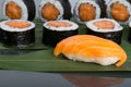 Close-up, on a dark table with a reflection, on a bamboo leaf, sushi and Japanese rolls with salmon