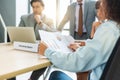 Close-up datasheet having casual discussion during meeting. Group of men and women sitting in office and smiling Royalty Free Stock Photo