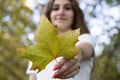 Close-up of a deciduous leaf being held by a young woman