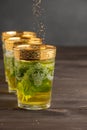 Close-up of decorated mint tea glasses, with brown sugar falling, selective focus, on dark wooden table, dark background Royalty Free Stock Photo