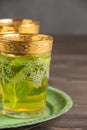 Close-up of decorated mint tea glasses, on green plate, selective focus, on dark wooden table, dark background Royalty Free Stock Photo