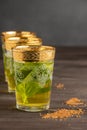 Close-up of decorated mint tea glasses, selective focus, on dark wooden table with brown sugar, dark background, vertical Royalty Free Stock Photo