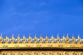 Decorative gold stucco thai syle patterns in temple on bright blue sky background with space